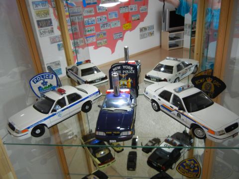 1999 Lincoln Town Car - Various police car models are displayed in a cabinet, some with flashing lights.