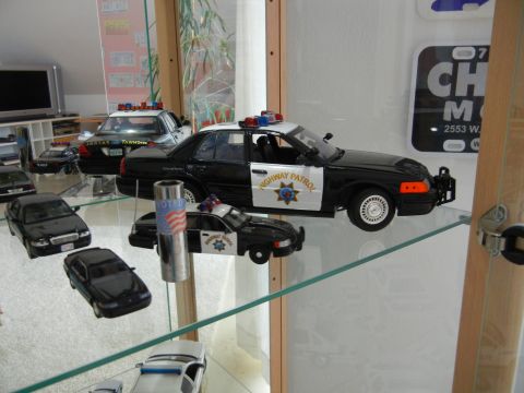 1999 Lincoln Town Car - Several model police cars are displayed on glass shelves, including a black and white patrol car.