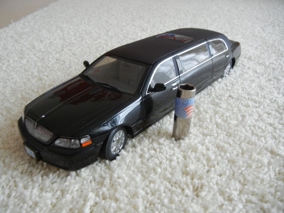 Black limousine model on white carpet, with a vote-themed socket tool