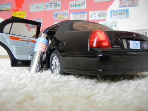 1999 Lincoln Town Car - A black 1999 Lincoln Town Car is shown from the rear with its driver's side door open, revealing a "Voted" sticker on a chrome cylinder.