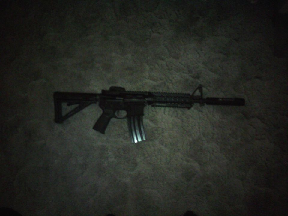 assault rifle with a magazine inserted, lying on a carpeted surface