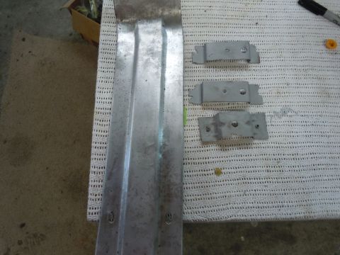 1970 Chevrolet Camaro - A close-up view of a metal car part and its associated mounting brackets, laid out on a textured surface.