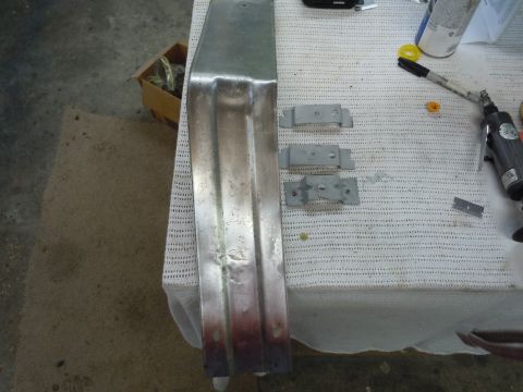 1970 Chevrolet Camaro - Metal car bumper and associated mounting brackets laid out on a table for repair or installation.