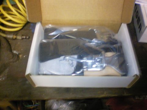 1989 Ford Bronco - A seatbelt buckle and strap are shown packaged inside a cardboard box.