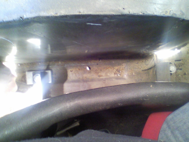 Interior view of a vehicle's floor pan with a seat mounting bracket visible