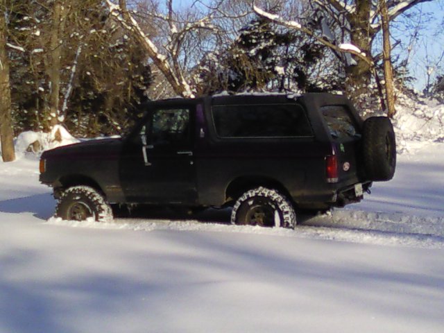 1989 Ford Bronco stuck in deep snow, side view. Spare tire mounted on rear door