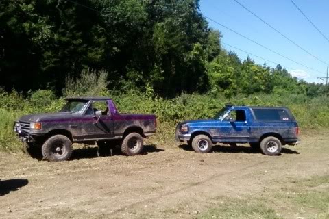 1989 Ford Bronco - Two Ford Broncos, a pickup conversion and a standard model, sit off-road on a sunny day.