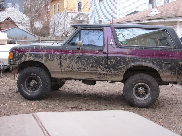 Side view of a muddy 1989 Ford Bronco with purple and black paint