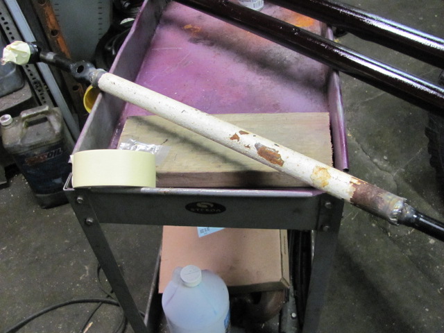 White painted metal rod with peeling paint and rust, taped ends, on a cart