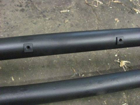 1989 Ford Bronco - Close-up view of two black metal tubes, possibly running boards or frame components, with visible square mounting points.
