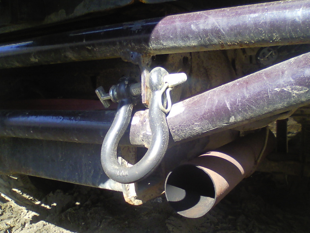 Tow hitch shackle and exhaust pipe on a vehicle's rear bumper