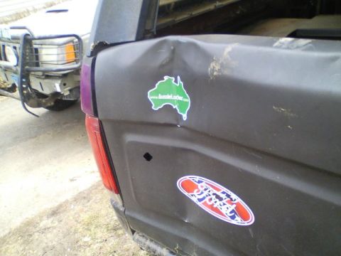 1989 Ford Bronco - A dented truck bed shows an Australia sticker and a Ford logo, with another vehicle in the background.