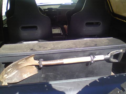 1989 Ford Bronco - A shovel is secured to a storage box behind the front seats of the vehicle.