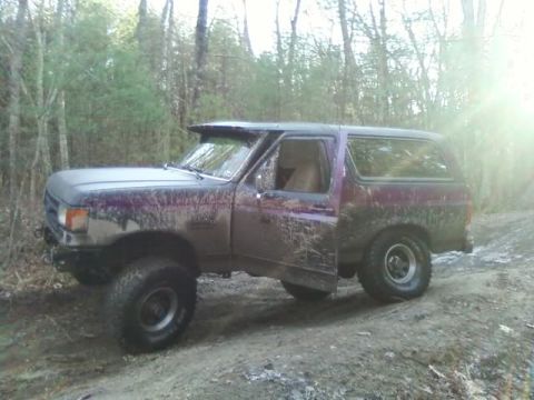 1989 Ford Bronco - This 1989 Ford Bronco is shown off-road, covered in mud with its doors open.