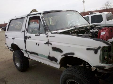 1995 Ford Bronco - This Ford Bronco is undergoing bodywork, with primer visible on its white exterior and the hood open.