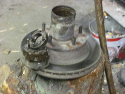 1989 Ford Bronco - Disassembled wheel hub and brake rotor components are shown resting on a wooden surface.