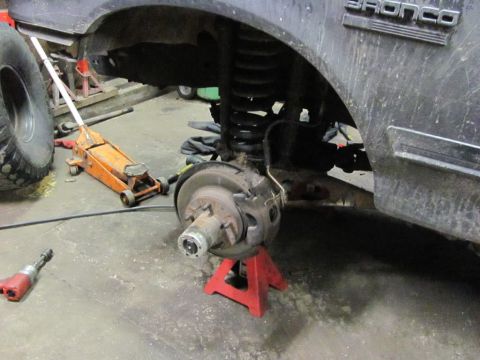 1989 Ford Bronco - Front wheel assembly of a Ford Bronco is disassembled, showing the brake and suspension components.