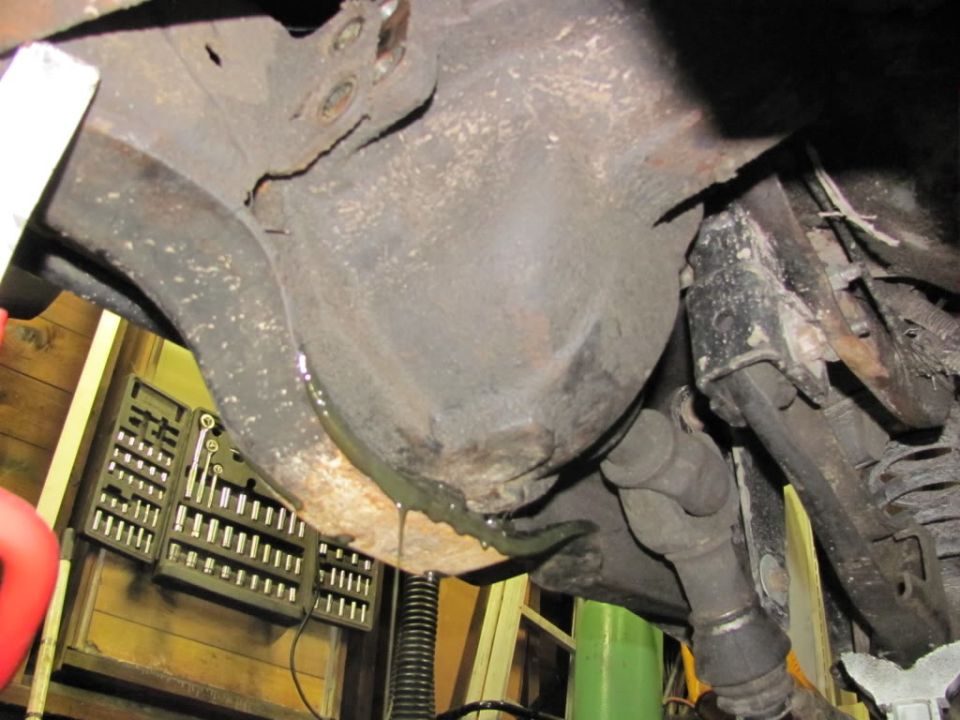 Underside view of a differential and driveshaft with a toolbox in the background