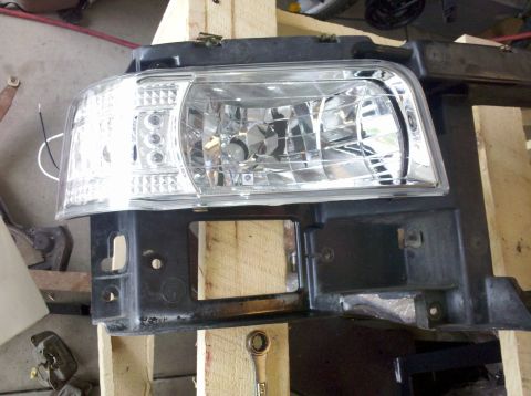 1995 Ford Bronco - A single headlight assembly is shown, detached from a vehicle and resting on wooden supports.