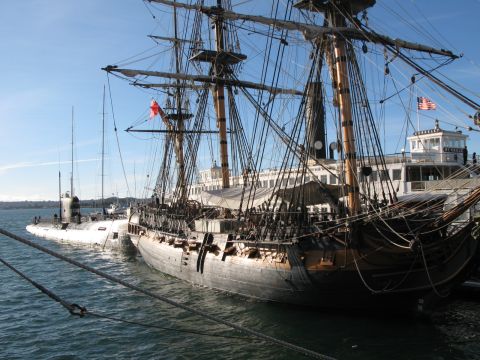 1971 Ford Ranchero - A historic tall ship is moored alongside a submarine, with a passenger ferry visible in the background under a clear blue sky.