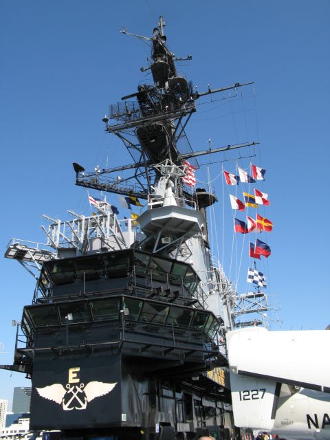 1971 Ford Ranchero - The complex superstructure of an aircraft carrier is adorned with numerous flags under a clear blue sky.