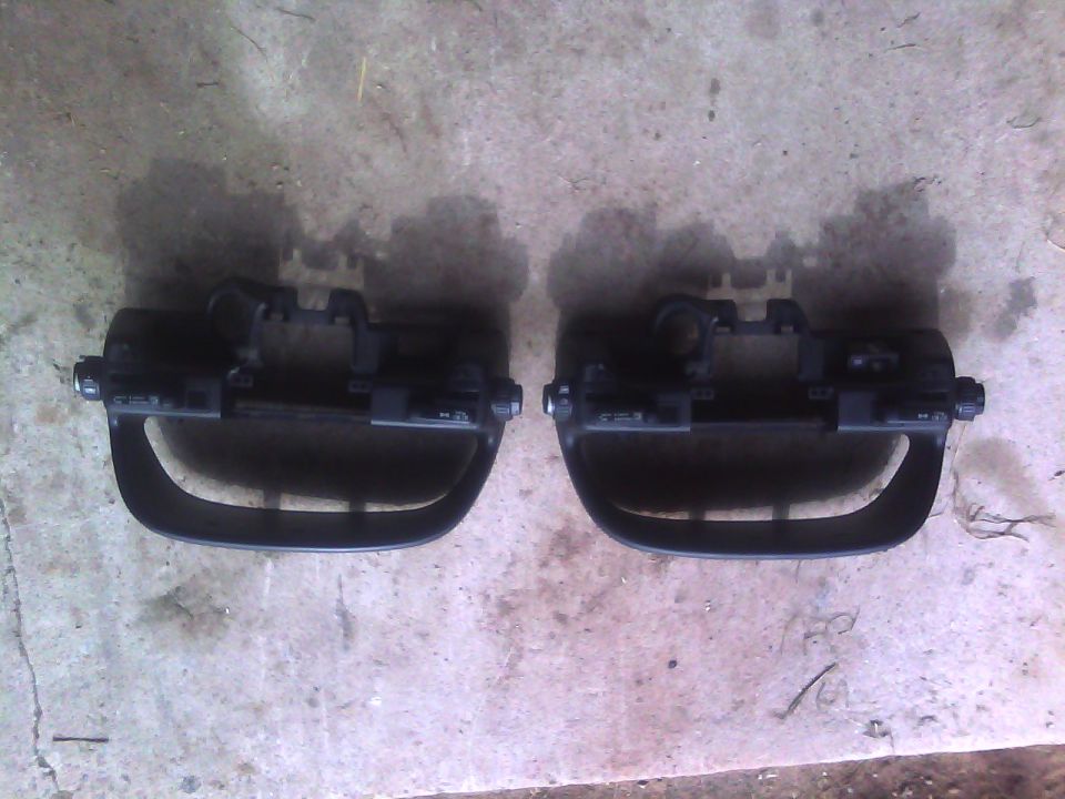 Two black plastic car interior trim pieces with mounting brackets and buttons, viewed from the front