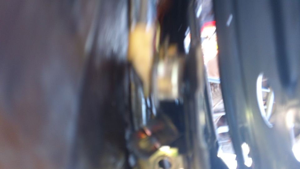 Blurry close-up into a gap between dark body panels showing gold-plated hardware