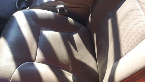 1994 Ford Bronco - The interior of a vehicle shows perforated leather seats, with light and shadow playing across the surfaces.