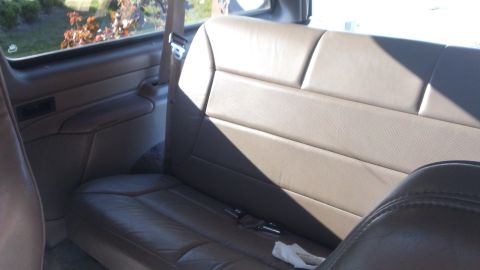 1994 Ford Bronco - Interior view of a vehicle's rear seating area, showing tan leather upholstery and door paneling.