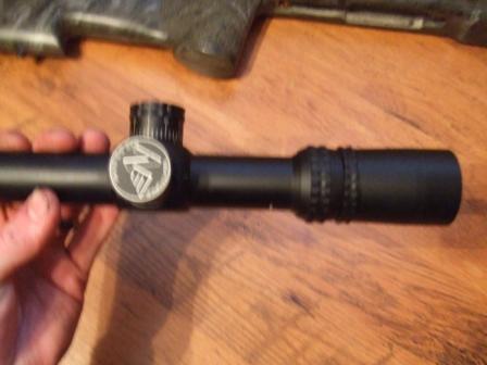 1996 Ford Bronco - A rifle scope is held in a hand, with a logo visible on its side.