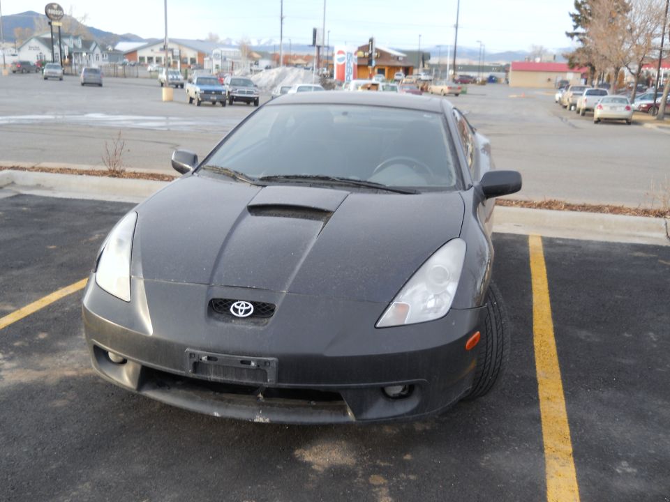 Dark gray Toyota Celica parked in a lot, front view. Hood scoop visible