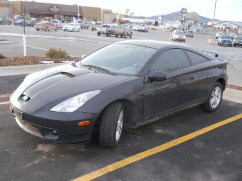 2006 Ford E350 - Front three-quarter driver's-side view of a black seventh-generation Toyota Celica hatchback coupe parked in a small-town lot, showing the…