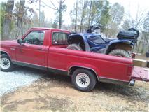 1995 Ford Bronco - Red pickup truck loaded with a blue ATV on a trailer ramp.