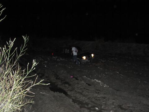 1981 Ford Bronco - Vehicle stuck in mud at night with headlights on.