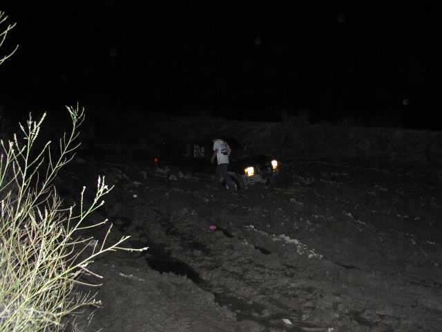 Off-road vehicle stuck in mud at night, headlights on