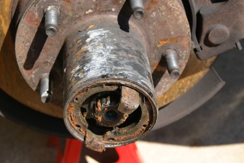 1978 Ford Bronco - Close-up view of a heavily rusted wheel hub assembly, revealing internal gears and lug nut mounting points.