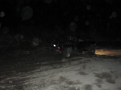 1981 Ford Bronco - Pickup truck navigates a dark, off-road path at night, illuminated by its headlights.