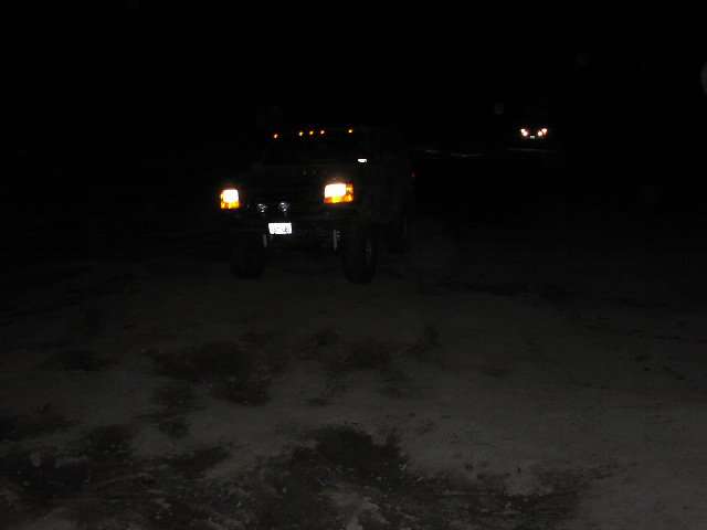 Truck with headlights on in the dark, parked on snow