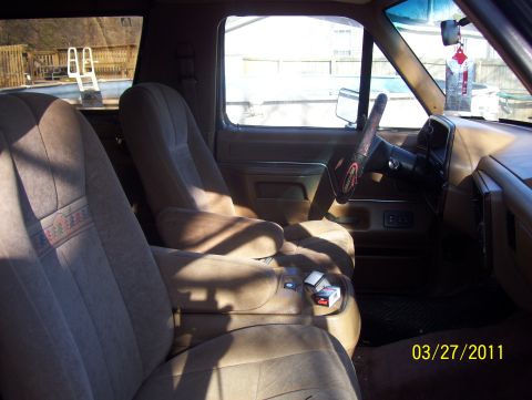 1990 Ford Bronco - The interior of a 1990 Ford Bronco shows tan cloth seats and a dashboard with a steering wheel.
