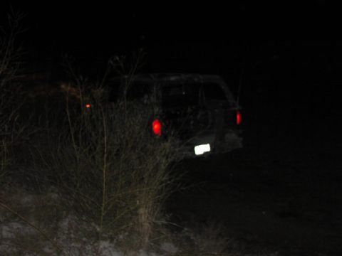 1981 Ford Bronco - A dark SUV is visible from the rear at night, with its taillights and license plate illuminated.