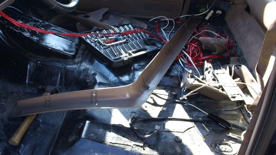 Stripped truck interior floor pan with tools, loose wiring and removed trim panel