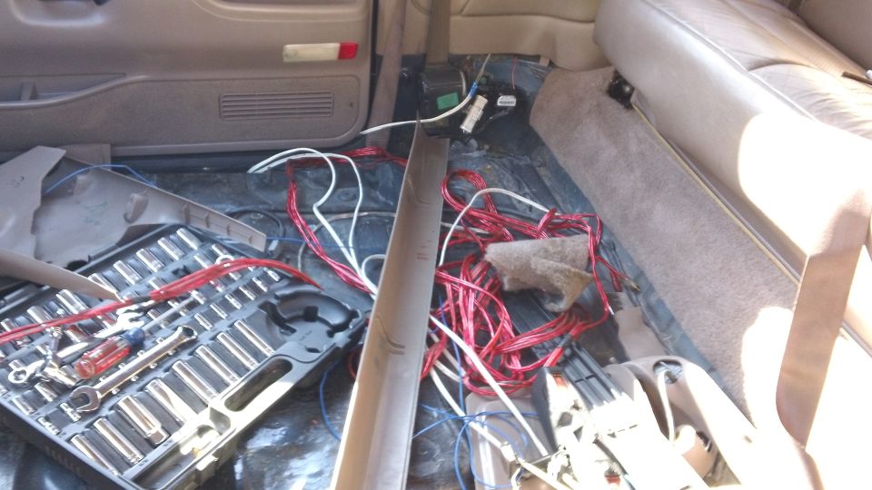 Truck interior teardown with pulled carpet, loose wiring, socket set and tan seats