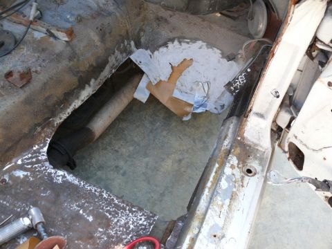 1976 Chevrolet Corvette - The interior floor of a car is undergoing repairs, with a section cut out to accommodate the exhaust system.