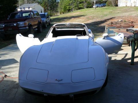 1976 Chevrolet Corvette - A white 1976 Chevrolet Corvette is parked outside with its doors open, showing its interior and front end.