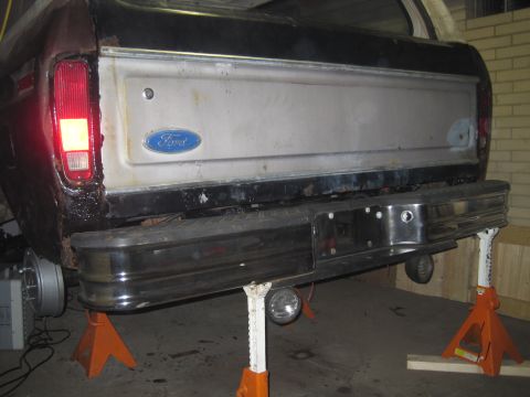 1979 Ford Bronco - The rear of a Ford pickup truck is shown elevated on jack stands, with the tailgate and bumper area in focus.