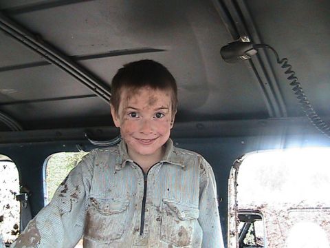 1978 Ford Bronco - A young boy, covered in mud, grins from inside a vehicle's interior.