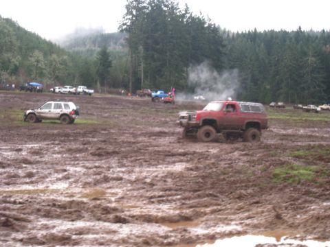1978 Ford Bronco - Several vehicles are navigating a challenging muddy terrain under an overcast sky.