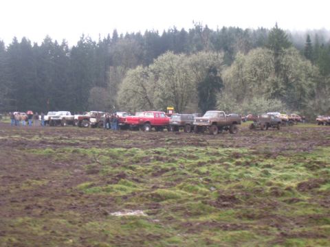 1978 Ford Bronco - Several off-road vehicles are gathered in a muddy field under an overcast sky.