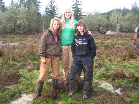 1978 Ford Bronco - Three young women pose for a photo in a muddy, outdoor environment, likely after participating in off-road activities.