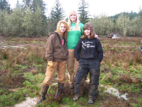 1978 Ford Bronco - Three young women pose in a muddy outdoor area with trees and brush.